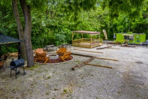 A fire pit sitting under a tree next to a tree.